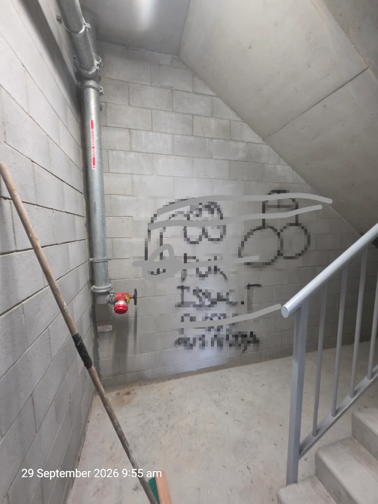 Before graffiti removal at a Tweed Heads strata property: stairwell wall with offensive markings obscured