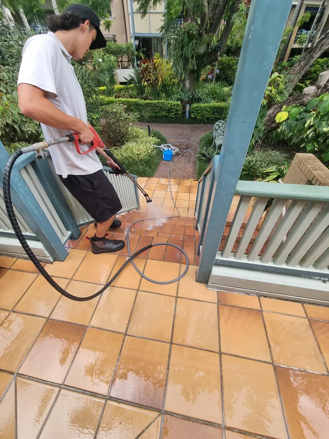 UP 2 Cleaning operator pressure-cleaning tiled stairs beside a residential patio at a Tweed Heads strata property